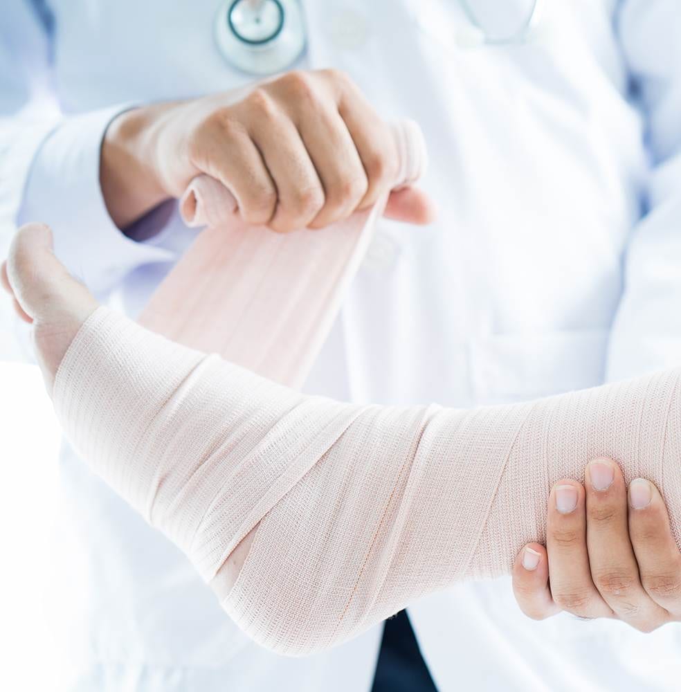 Close-up of male doctor bandaging foot of patient at doctor's office.