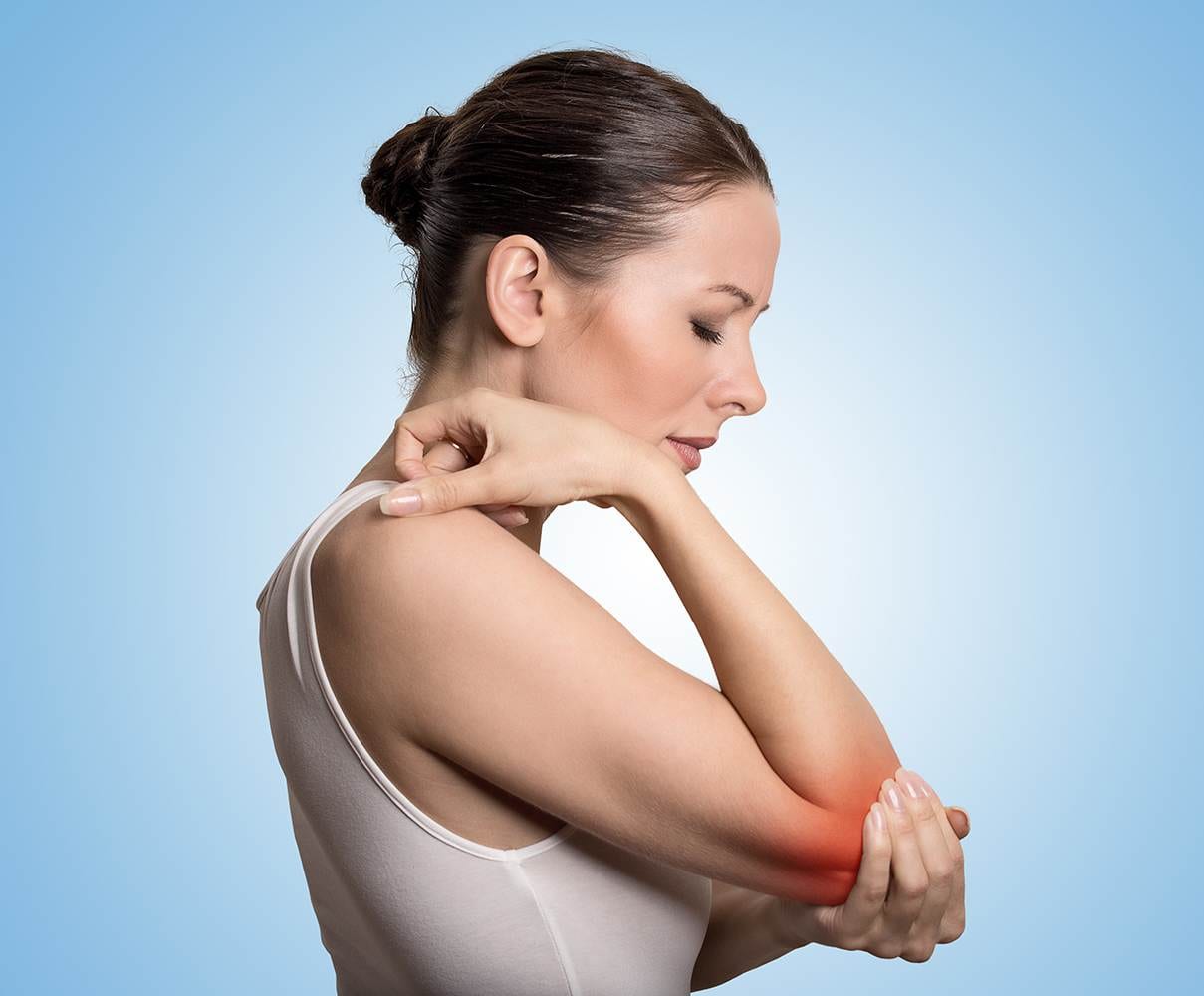 Joint inflammation indicated with red spot on female's elbow. Arm pain and injury concept. Closeup portrait woman with painful elbow on blue background